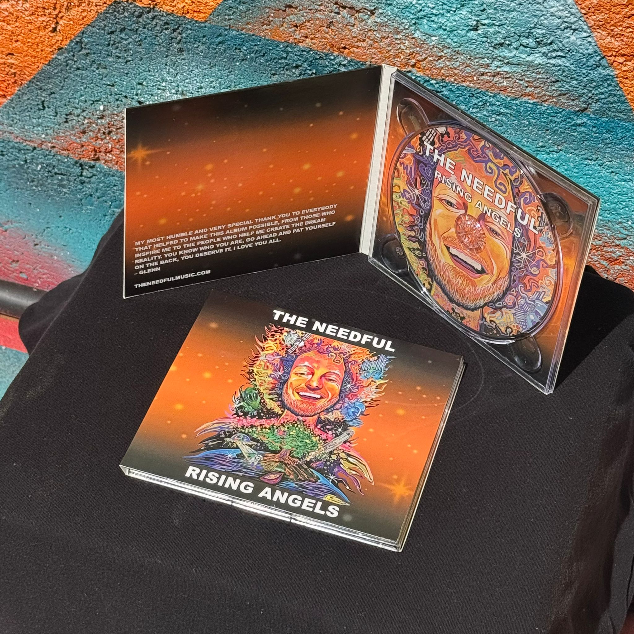two cd cases for rising angels album, one laying flat on a table, the other open to see the artwork.