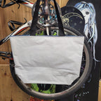 White recycled tote bag attached to a bicycle with a colorful background