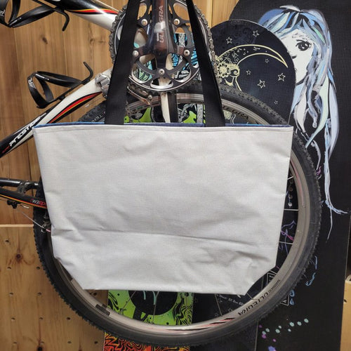 White recycled tote bag attached to a bicycle with a colorful background