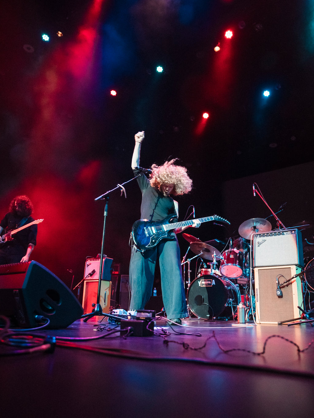 Canadian band The Needful, Glenn on stage with raised fist, surrounded by band equipment under colorful lights
