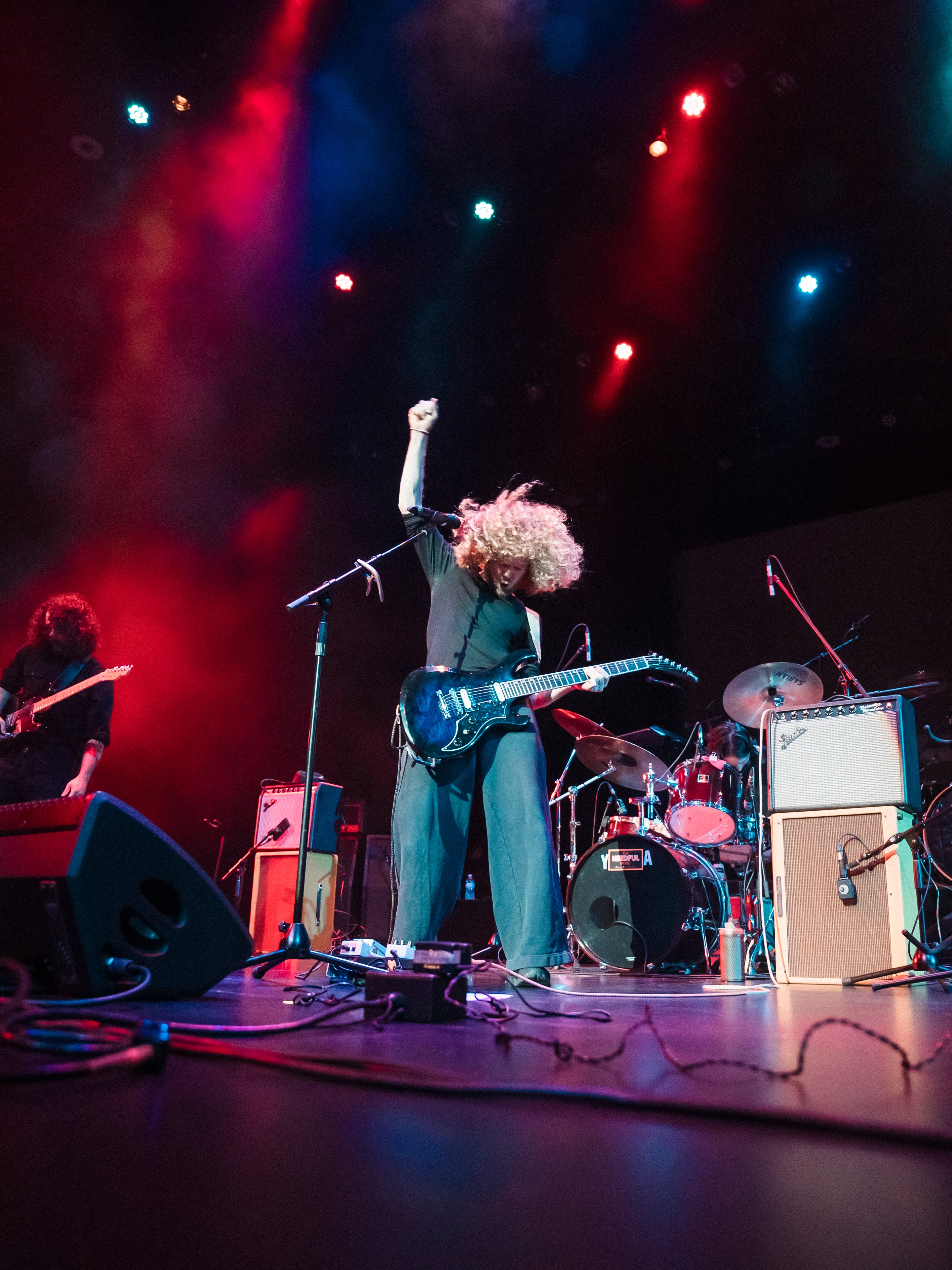 Canadian band The Needful, Glenn on stage with raised fist, surrounded by band equipment under colorful lights