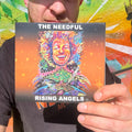 travis holding up a booklet fro the cd for the needfuls latest album, rising angels.