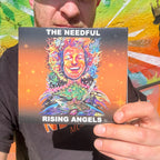 travis holding up a booklet fro the cd for the needfuls latest album, rising angels.